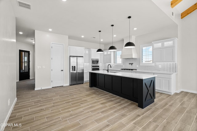 kitchen with stainless steel appliances, visible vents, a sink, and decorative backsplash