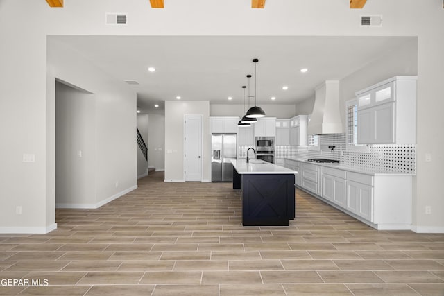 kitchen with custom exhaust hood, visible vents, appliances with stainless steel finishes, and decorative backsplash