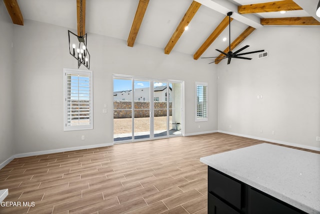 unfurnished living room with wood finish floors, beam ceiling, visible vents, baseboards, and ceiling fan with notable chandelier