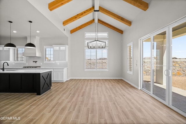 kitchen featuring light countertops, light wood-type flooring, decorative backsplash, cooktop, and custom range hood