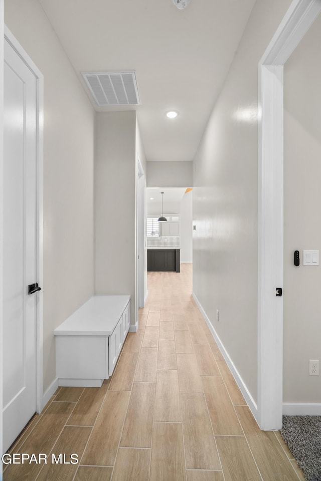 hall featuring wood finish floors, visible vents, and baseboards