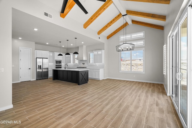 kitchen featuring visible vents, custom range hood, appliances with stainless steel finishes, and open floor plan