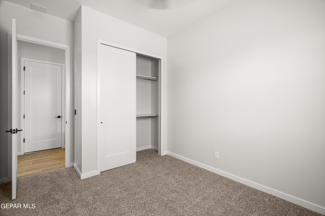 unfurnished bedroom with a closet, carpet, visible vents, and baseboards