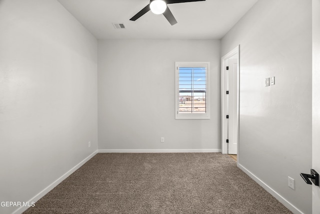 carpeted spare room featuring baseboards, visible vents, and ceiling fan