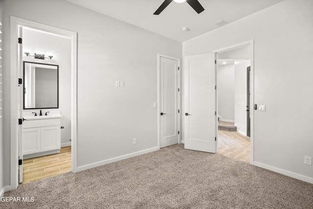 unfurnished bedroom featuring light carpet, visible vents, baseboards, ensuite bath, and ceiling fan