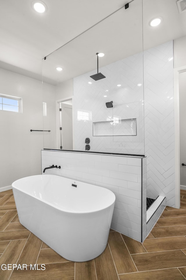 bathroom featuring wood tiled floor, visible vents, a walk in shower, and a freestanding bath