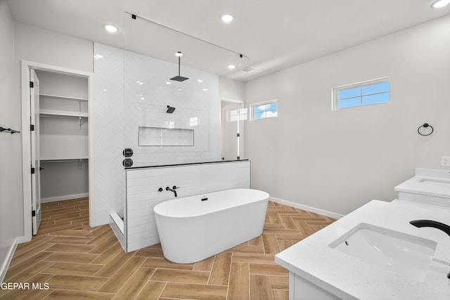 full bathroom with double vanity, recessed lighting, a freestanding bath, a sink, and walk in shower