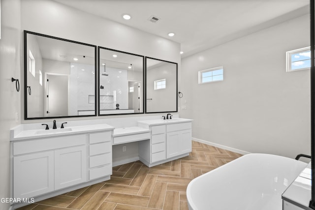 full bathroom with double vanity, a freestanding bath, visible vents, and a sink