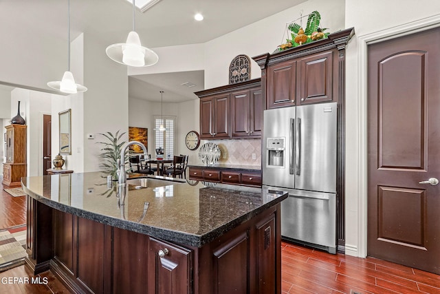 kitchen featuring stainless steel fridge with ice dispenser, sink, hanging light fixtures, a center island with sink, and dark hardwood / wood-style flooring