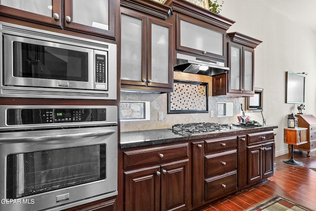 kitchen with dark brown cabinets, dark wood-type flooring, stainless steel appliances, and tasteful backsplash