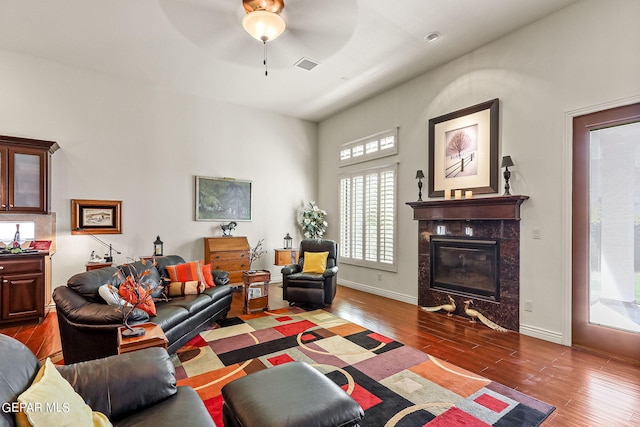 living room featuring ceiling fan, dark hardwood / wood-style floors, and a fireplace