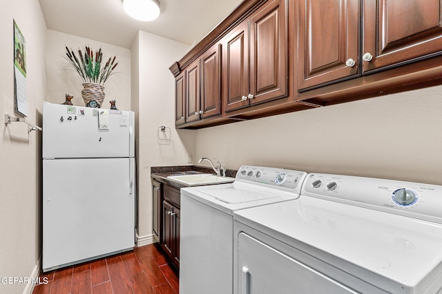 washroom with cabinets, dark hardwood / wood-style floors, sink, and washing machine and dryer