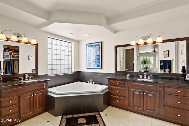 bathroom with ceiling fan, tile patterned floors, tiled tub, and vanity