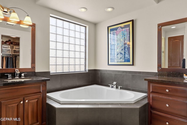 bathroom with plenty of natural light, vanity, and a relaxing tiled tub