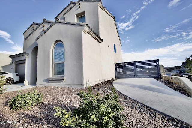 view of side of home with a tile roof, stucco siding, and an attached garage