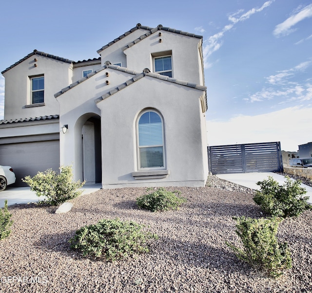 mediterranean / spanish home featuring a tile roof, a garage, and stucco siding
