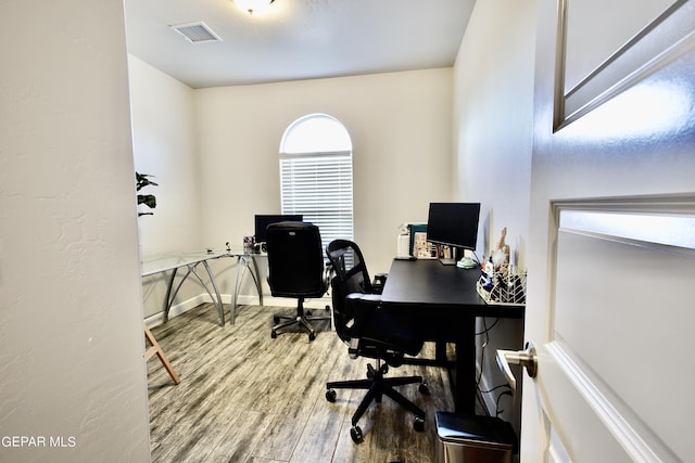 office space featuring wood finished floors, baseboards, and visible vents