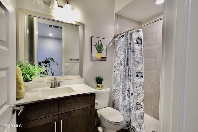 bathroom featuring visible vents, toilet, tiled shower, and vanity