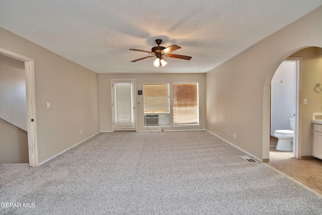 empty room with light carpet, a textured ceiling, cooling unit, and ceiling fan