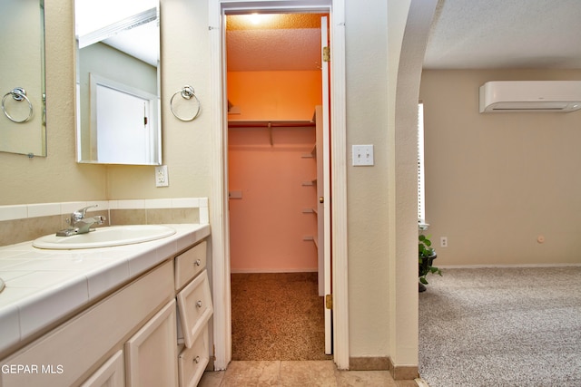 bathroom featuring a wall mounted AC, vanity, a textured ceiling, and tile patterned flooring