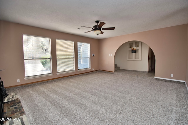 unfurnished living room featuring ceiling fan, a textured ceiling, and light colored carpet