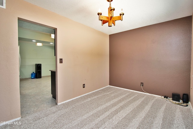 unfurnished room featuring a notable chandelier, a textured ceiling, and light carpet