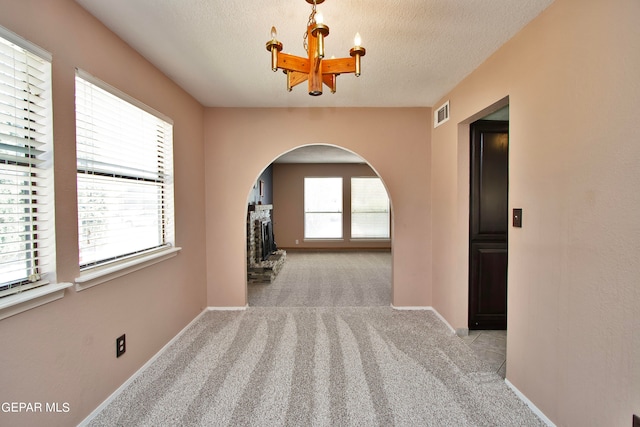 interior space featuring a textured ceiling, light colored carpet, and a chandelier