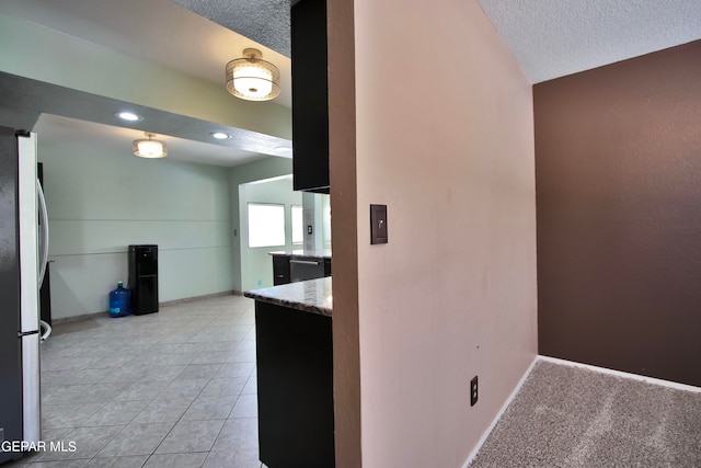 kitchen featuring a textured ceiling, dishwasher, stainless steel fridge, vaulted ceiling, and light colored carpet