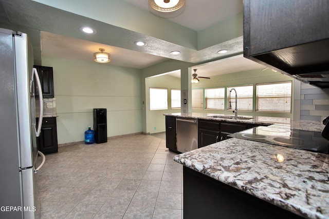 kitchen featuring light tile patterned floors, stainless steel appliances, light stone counters, ceiling fan, and sink