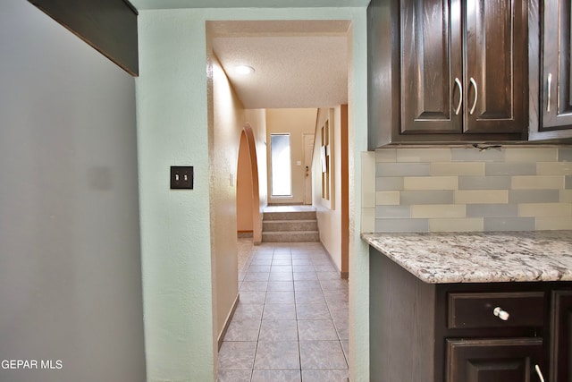 hallway with a textured ceiling and light tile patterned floors