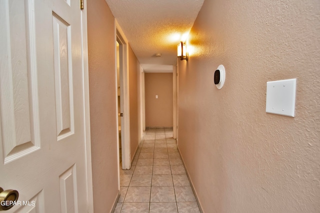 hallway featuring a textured ceiling and light tile patterned floors