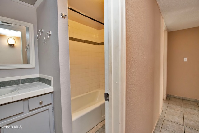 bathroom featuring a textured ceiling, tiled shower / bath combo, vanity, and tile patterned floors