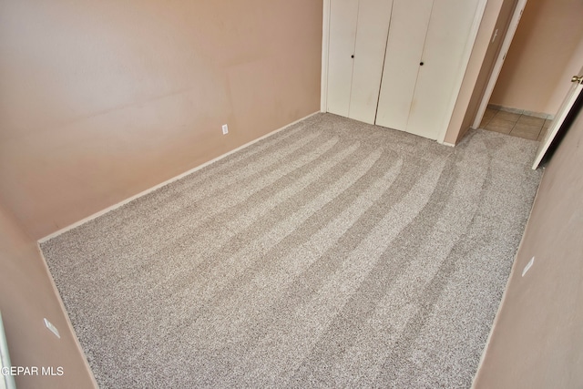 unfurnished bedroom with light colored carpet and a closet