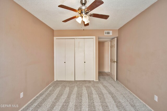 unfurnished bedroom with light carpet, a textured ceiling, a closet, and ceiling fan