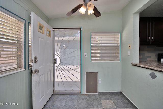 doorway with ceiling fan and light tile patterned flooring