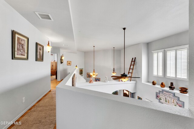 interior space featuring ceiling fan, light wood-type flooring, kitchen peninsula, and pendant lighting