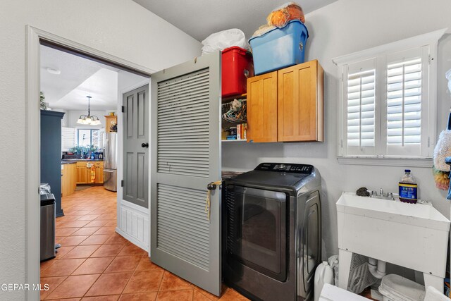 washroom featuring sink, a notable chandelier, cabinets, light tile patterned floors, and washer / dryer