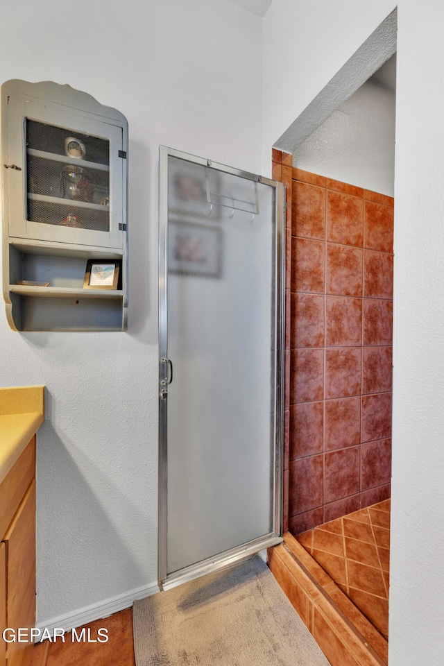 bathroom with tile patterned flooring, a shower with door, and vanity