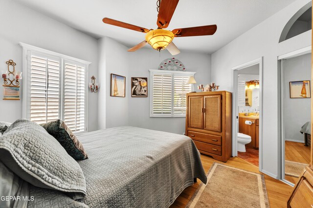 bedroom featuring ceiling fan, light hardwood / wood-style flooring, and ensuite bath