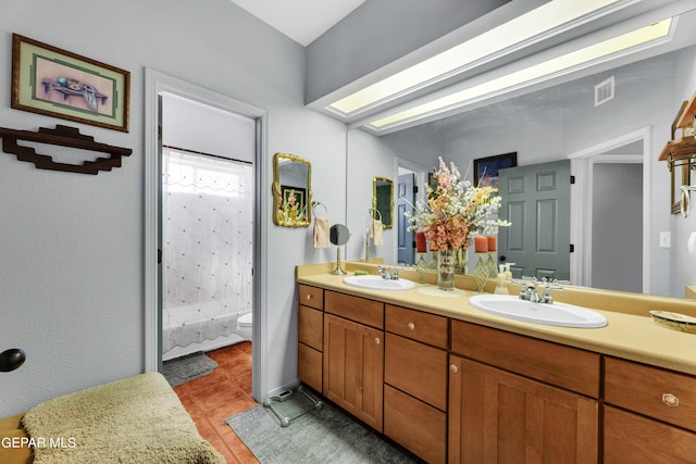 bathroom featuring tile patterned floors, dual bowl vanity, and toilet