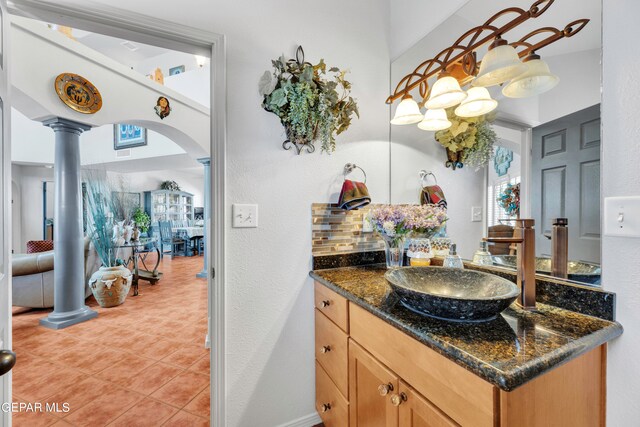 bathroom with ornate columns, tile patterned floors, decorative backsplash, and vanity