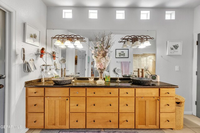 bathroom featuring dual vanity, a towering ceiling, and tile patterned floors