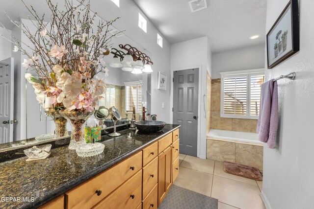 bathroom with tile patterned floors, tiled tub, and vanity