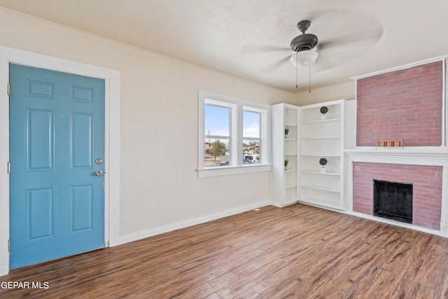 interior space featuring ceiling fan, a fireplace, a textured ceiling, and hardwood / wood-style floors