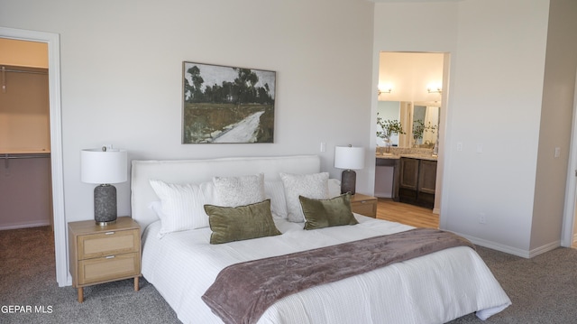 carpeted bedroom with a walk in closet, a closet, and ensuite bathroom