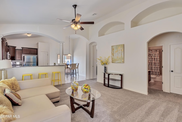 carpeted living room with ceiling fan and high vaulted ceiling