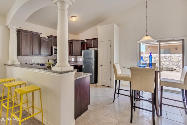 kitchen with light tile patterned floors, appliances with stainless steel finishes, vaulted ceiling, backsplash, and ornate columns