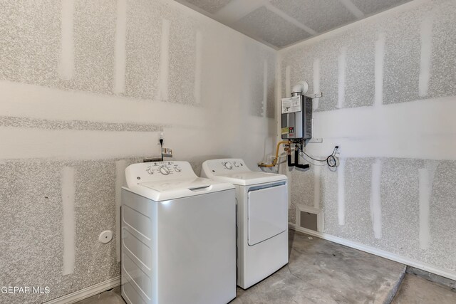 clothes washing area with tankless water heater and washing machine and clothes dryer