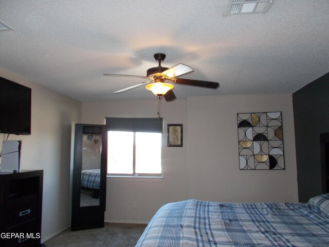 bedroom featuring ceiling fan, a textured ceiling, and carpet floors