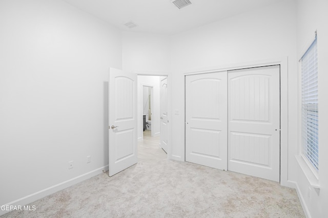 unfurnished bedroom with light carpet and a closet